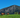 Horses grazing on a grassy field with a mountainous background